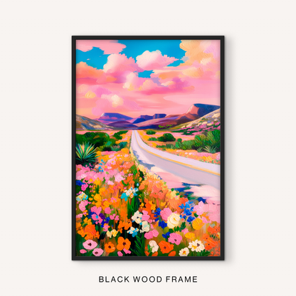 Boho western landscape print in a black frame featuring a pink sky, desert road, wildflower meadow, and southwestern mountains.