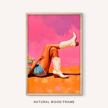 Feminine western wall art in a natural wood frame with white cowgirl boots, pink and orange painted background, and modern cowgirl style.