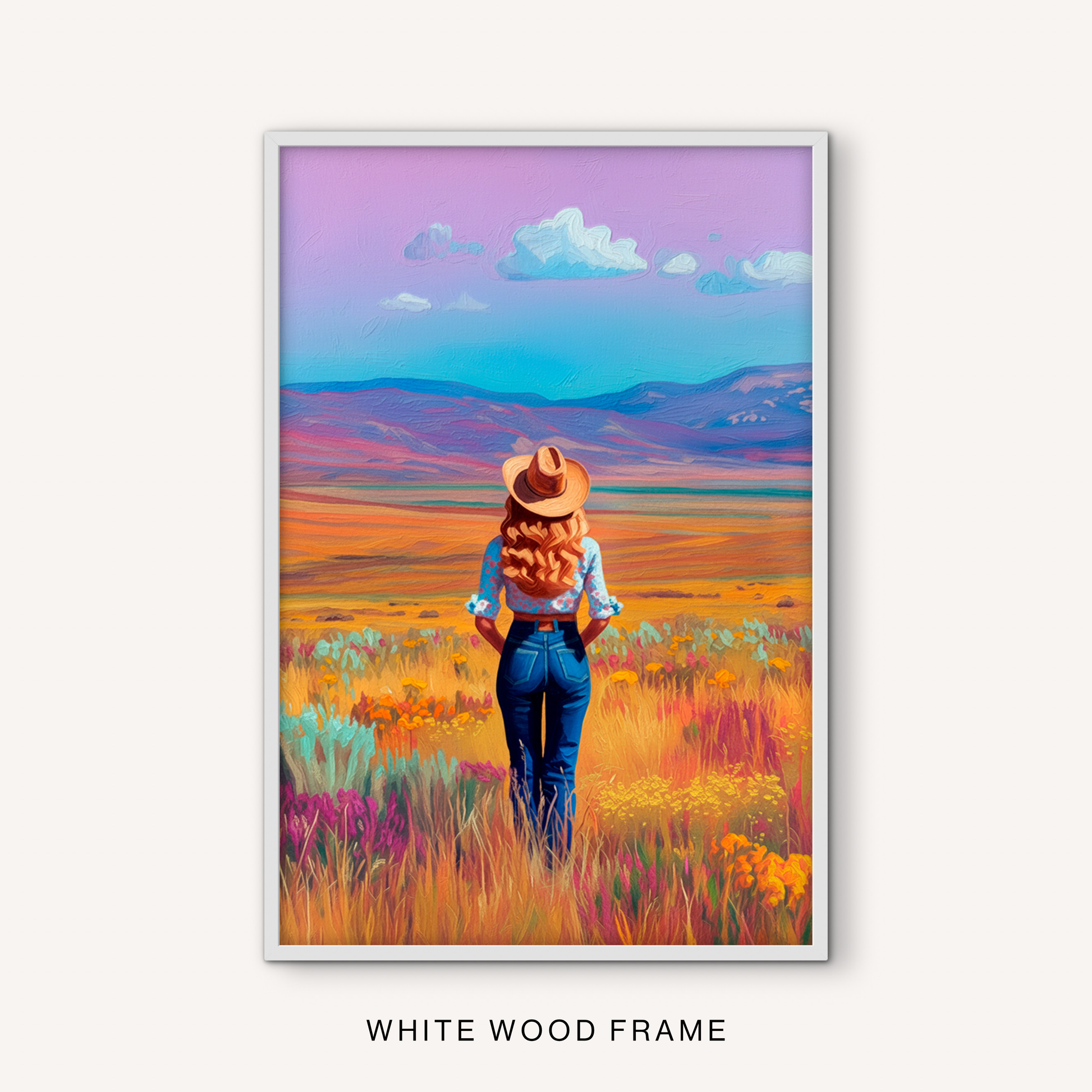 Western cowgirl wall art in a white frame with a colorful meadow, open prairie, mountain view, and soft blue and lavender sky.