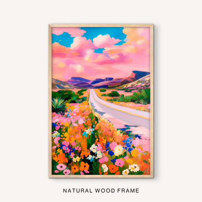 Maximalist desert flower wall art in a natural wood frame with a colorful western landscape, winding road, and pink sunset sky.