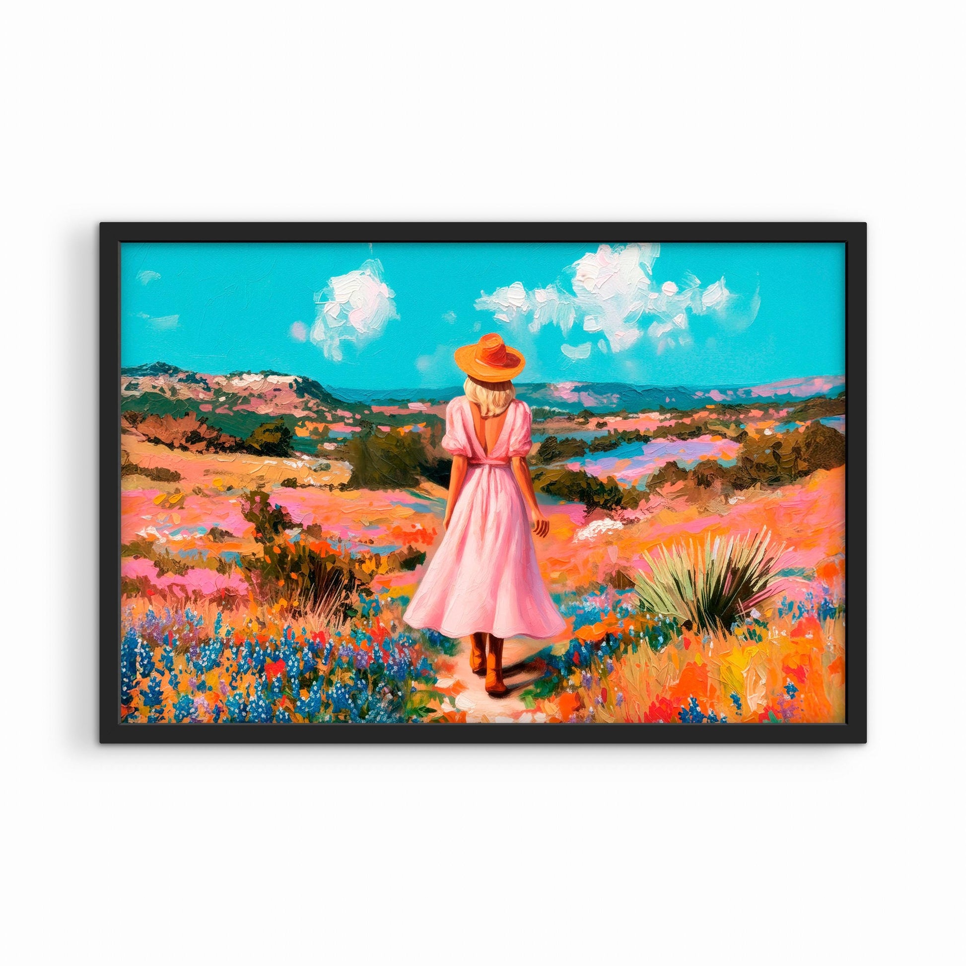 Framed western landscape print in a black frame featuring a woman walking through a colorful field of wildflowers