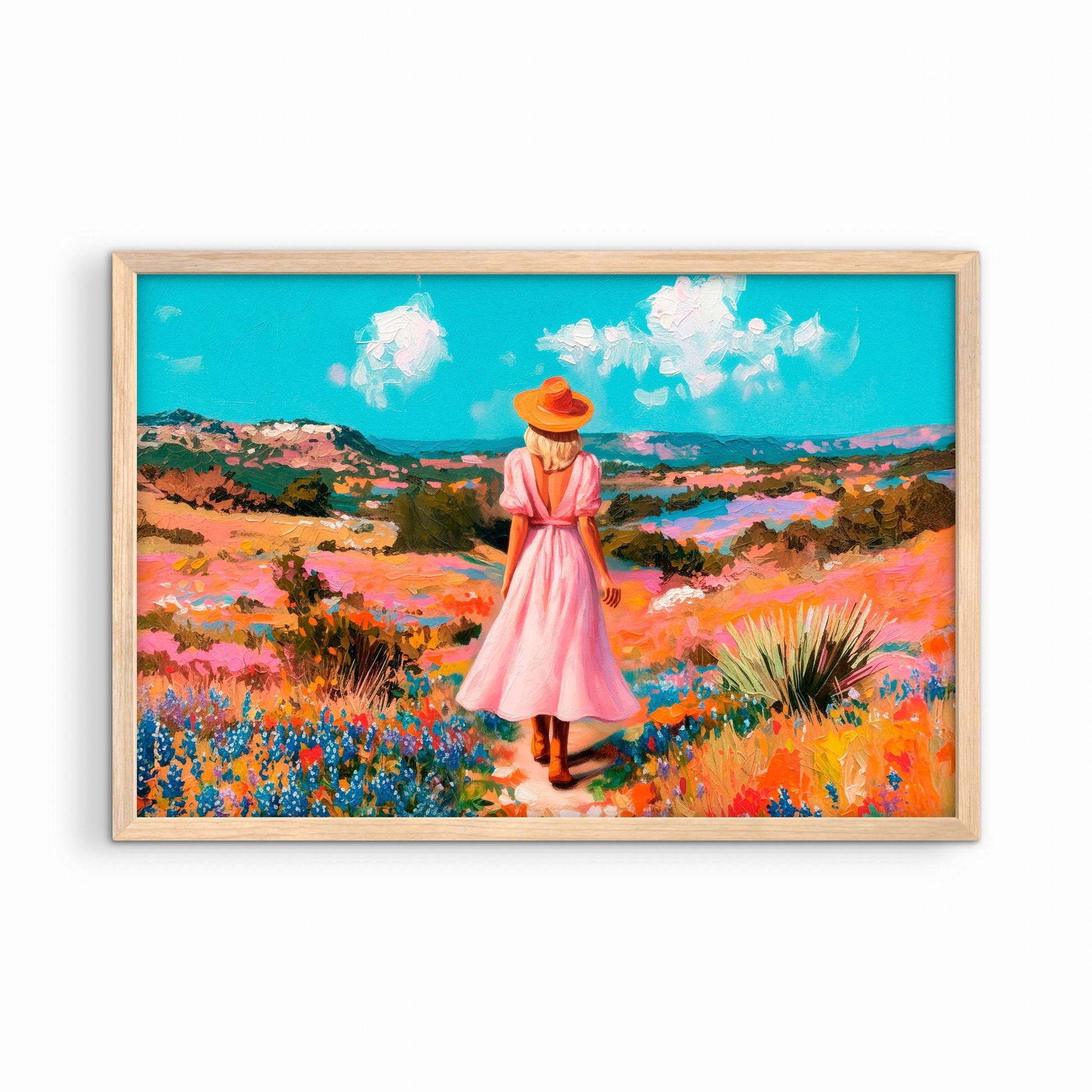 Western landscape art print in a natural wood frame featuring a woman walking through wildflowers in a bright countryside scene